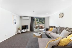 a living room with a couch and a tv at Central Mountain View Paradise in Queenstown