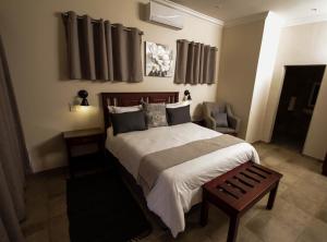 a bedroom with a large bed and a chair at New Haven Guest House (Pty) Ltd in Newcastle
