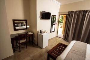 a bedroom with a bed and a desk and a television at New Haven Guest House (Pty) Ltd in Newcastle