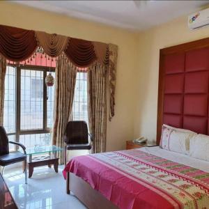 a bedroom with a bed and a chair and windows at Hotel Imperial Karachi in Karachi