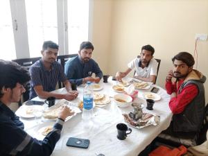 a group of men sitting around a table eating food at Ringachan Guest House & Restaurant in Skardu +18 photos