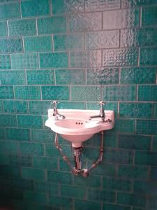 a bathroom with a sink in a green tiled wall at Wheelers Bay Apartment in Ventnor