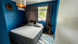 a small blue room with a bed and a window at MANUNU LODGE 2 days minim in Faaa