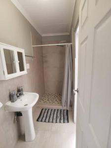 a white bathroom with a sink and a shower at HadedaOpiHoek in Postmasburg