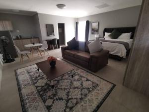 a bedroom with a bed and a couch and a table at HadedaOpiHoek in Postmasburg