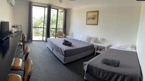 Habitación de hotel con 2 camas y ventana en Jumbuck Motor Inn - POOL - PET FRIENDLY SECTION - KING BEDS, en Longreach