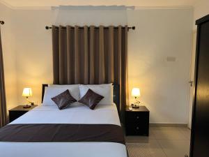 sypialnia z łóżkiem z 2 poduszkami i 2 lampami w obiekcie Paul's Residence w Mahé