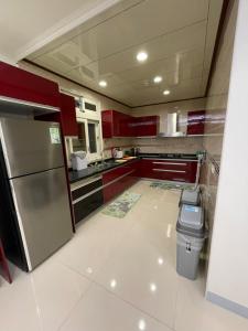 eine Küche mit roten Schränken und einem Kühlschrank aus Edelstahl in der Unterkunft Fun Hotspring in Jiaoxi