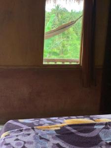 a bedroom with a window with a blanket on a bed at Tetebatu Sama Sama Bungalows in Tetebatu