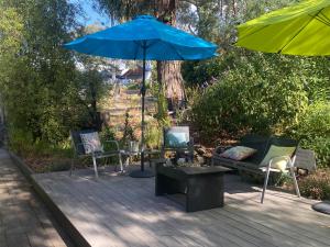 a patio with chairs and a blue umbrella and a table at Spa Suites at RAVEN in Hepburn Springs