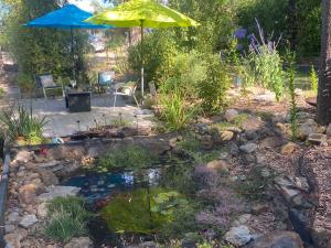a koi pond with an umbrella in a garden at Spa Suites at RAVEN in Hepburn Springs