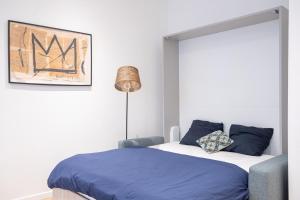 um quarto com uma cama com lençóis azuis e um candeeiro em Le Sweet Forville 2 - Palais des Festivals - Marché provençal - Plage - Clim - Au calme em Cannes