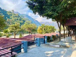 una fila de bancos con montañas en el fondo en Euphoric River Resort en Rishīkesh