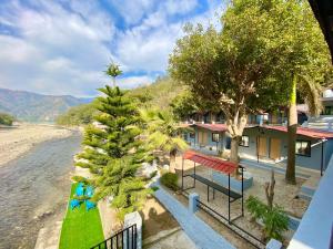 a resort with a palm tree next to a body of water at Euphoric River Resort in Rishīkesh