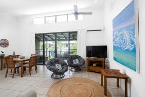 a living room with chairs and a tv and a table at Rainbow Shores - 2 Bedroom, modern apartment, sleeps 6, pool, walk to the beach in Rainbow Beach