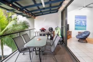 a dining room with a table and chairs on a balcony at Rainbow Shores - 2 Bedroom, modern apartment, sleeps 6, pool, walk to the beach in Rainbow Beach