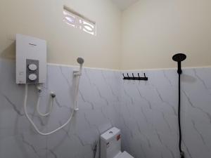 a white bathroom with a toilet and a shower at 83 Guesthouse in Bahal