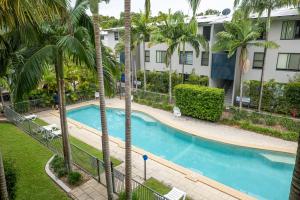 Una piscina con palmeras frente a un edificio. en Rainbow Shores Resort Getaway!, en Rainbow Beach