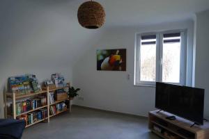 a living room with a flat screen tv and a book shelf at Casa de Alpaca in Schmelz