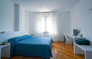 a bedroom with a bed and a desk and a window at Hotel Mistral in Oristano