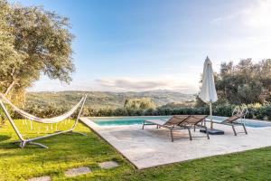 een zwembad met 2 stoelen, een hangmat en een parasol bij Apithano Heated pool on demand in Spiliá