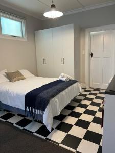 a bedroom with a bed and a black and white checkered floor at Beach Front Studio Napier in Napier