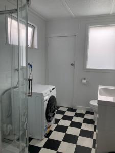 a bathroom with a washing machine on a checkered floor at Beach Front Studio Napier in Napier