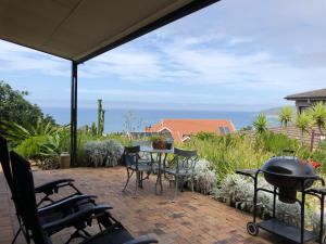 a patio with a table and chairs and a grill at Wilderness Ocean View Cottage 1 in Wilderness