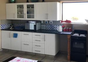 a kitchen with white cabinets and a black counter top at Wilderness Ocean View Cottage 1 in Wilderness