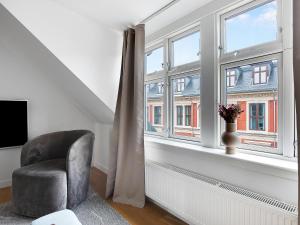 een woonkamer met een stoel en een raam bij Sanders Leaves - Precious Two-Bedroom Penthouse In Downtown Copenhagen in Kopenhagen