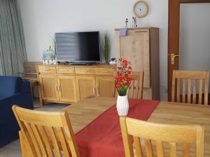 uma mesa de jantar com um vaso de flores em Appartement Buesum GT33-4 em Büsum