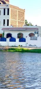 a white building next to a body of water at Villa Victoria Old Nile View in Luxor