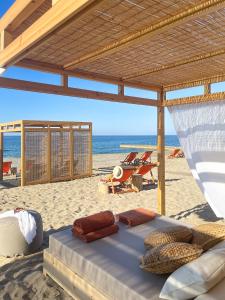 een bed op een strand met stoelen en de oceaan bij Aquila Rithymna Beach in Adelianos Kampos