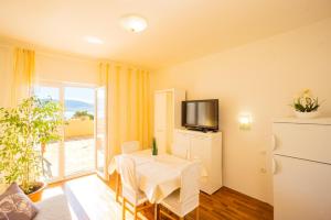 a dining room with a white table and a television at Marva stylish Mediterranean accomodation with beautiful view in Zubovići