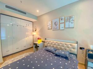een slaapkamer met een blauw bed en een witte muur bij Sea View Sandy homestay Citadines Marina Ha Long in Ha Long