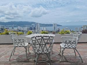 a table and chairs on a patio with a view of the city at Casa Horizonte Azul Acapulco in Acapulco