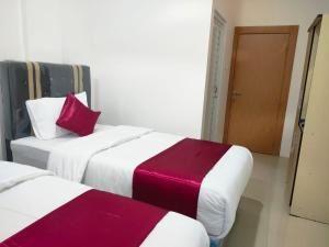 2 Betten mit roter und weißer Bettwäsche in einem Zimmer in der Unterkunft Hiast Syariah Residence in Palembang