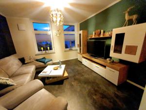 een woonkamer met een bank en een tv bij Ferienwohnung ODIN, FREYA & THOR in Thale