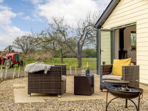 a patio with wicker chairs and a fire pit at Bramley Cottage in North Weald