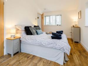 um quarto com uma cama branca e piso em madeira em Bramley Cottage em North Weald