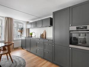 a kitchen with gray cabinets and a table with a chair at Regent 4- Cute 1-Bdr Apt in Centre of Copenhagen in Copenhagen