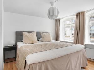 1 dormitorio blanco con 1 cama grande y 2 ventanas en Sanders Regent - Endearing One-Bedroom Apartment Near Central Square en Copenhague