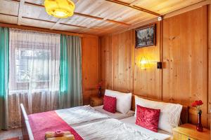 1 dormitorio con 1 cama con almohadas rojas y blancas en Ferienhaus Wechner, en Häselgehr