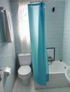 a bathroom with a toilet and a blue shower curtain at Hotel El Molino in Ciudad Real