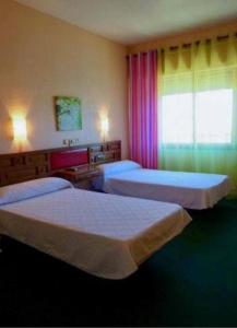 シウダー・レアルにあるHotel El Molinoのベッド2台と窓が備わるホテルルームです。