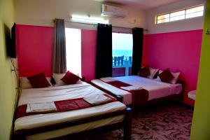 two beds in a room with pink walls and windows at Paradise Harmony Beach Resort in Singānallūr