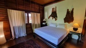 1 dormitorio con 1 cama blanca en una habitación con paredes de madera en BEACH HOUSE WOODY, en Laem Sor