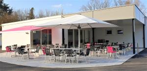 a group of tables and chairs with an umbrella at Camping de l'Ill in Mulhouse