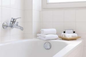 uma banheira branca com toalhas e um lavatório em Wyndham Garden Donaueschingen em Donaueschingen