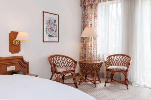 um quarto com 2 cadeiras, uma cama e uma janela em Wyndham Garden Donaueschingen em Donaueschingen